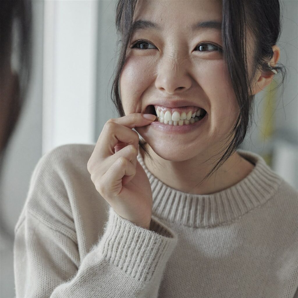 거울로 송곳니 덧니 배열을 확인하며 웃는 모습