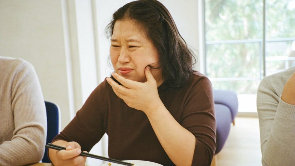 씹을 때 치아 통증으로 볼을 감싼 여성